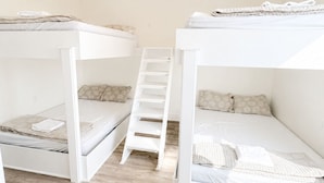 Een kamer met twee stapelbedden, een houten vloer en een trap.