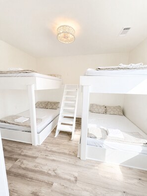 A room with two bunk beds, a wooden floor, and a staircase. - Baywinds condo #9: Spacious 4BR waterfront retreat in Grand Isle, LA. - Coastal Realty Group (Grand Isle)
