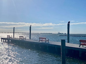 Eine Uferpromenade mit Bänken und einem Steg, der sich ins Wasser erstreckt.