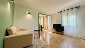 A living room with a sofa, a TV, and a dining area with chairs and a table.