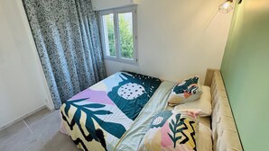 A bedroom with a bed, patterned curtains, a window, and a wall-mounted light fixture.