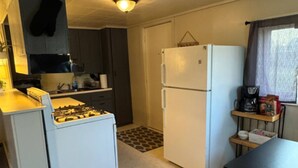 A compact kitchen with a stove, refrigerator, and a small dining area.