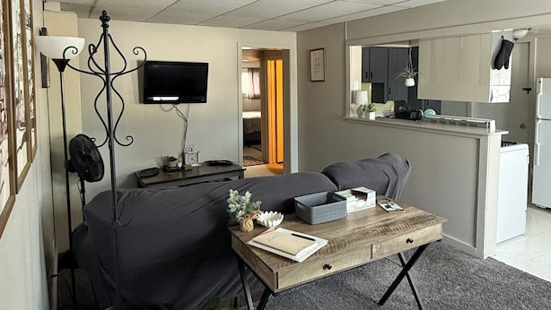 A compact living space with a sofa, coffee table, and a TV. There is a kitchenette area with a fridge and microwave.