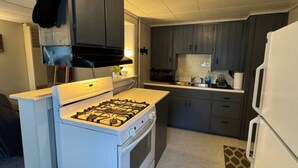 A compact kitchen with a gas stove, white cabinets, and a refrigerator.