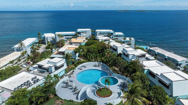 A resort with multiple buildings, a central pool, and a view of the ocean. - New central located 2BR/3BD/2BA condo gated community with 2 pools & pickleball (St Thomas)
