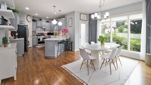 A modern kitchen with a central island, white cabinetry, and a dining area with a round table and chairs. - Family-Friendly 5BR Home w/ Games & Massage Chair (Papillion)