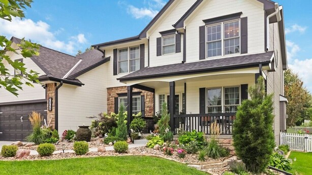 A two-story house with a covered porch, a stone foundation, and a well-maintained garden. - Family-Friendly 5BR Home w/ Games & Massage Chair (Papillion)