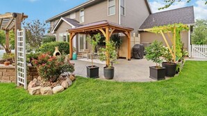 A two-story house with a covered patio, a stone retaining wall, and potted plants. - Family-Friendly 5BR Home w/ Games & Massage Chair (Papillion)