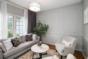 A living room with a sofa, armchair, round coffee table, and a large plant. - Family-Friendly 5BR Home w/ Games & Massage Chair (Papillion)