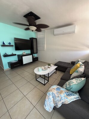 A living room with a TV, sofa, coffee table, and decorative items.