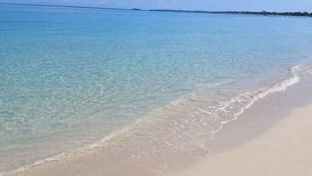 Ein Strand mit klarem türkisblauem Wasser und einem sandigen Ufer.