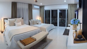 Ein modernes Hotelzimmer mit zwei Betten, einem Deckenventilator, einem Fernseher und einem Balkon mit Blick.