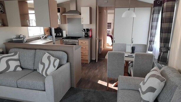 Un espacio habitable compacto con sofá, mesa de comedor y kitchenette.