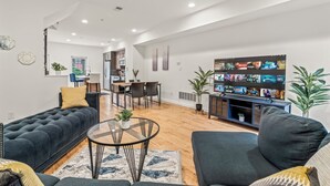 A modern living room with a dark blue sofa, a round coffee table, and a TV displaying a movie.