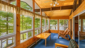Une cabane dotée de grandes fenêtres, d’un ventilateur de plafond et d’un sol recouvert d’une moquette bleue.