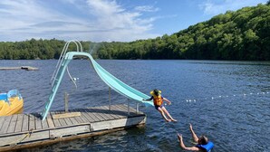 A wooden dock extending into a lake with a slide leading into the water.