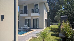 A modern two-story building with a swimming pool, outdoor seating, and a well-maintained lawn. - Villa Mariposa - Luxury Summer Residence (Turgutköy)