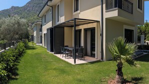 A modern two-story house with a covered patio, a balcony, and a well-maintained lawn. - Villa Mariposa - Luxury Summer Residence (Turgutköy)