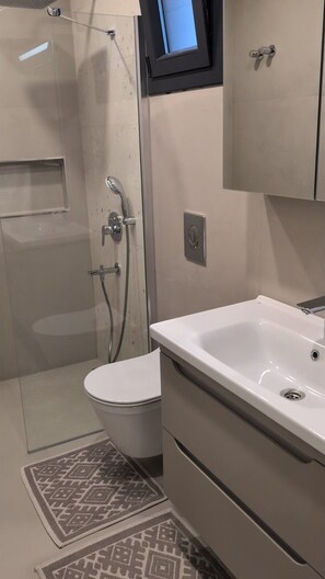A modern bathroom with a shower, toilet, and sink.