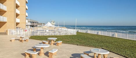 A beachfront patio with outdoor seating and a view of the ocean.