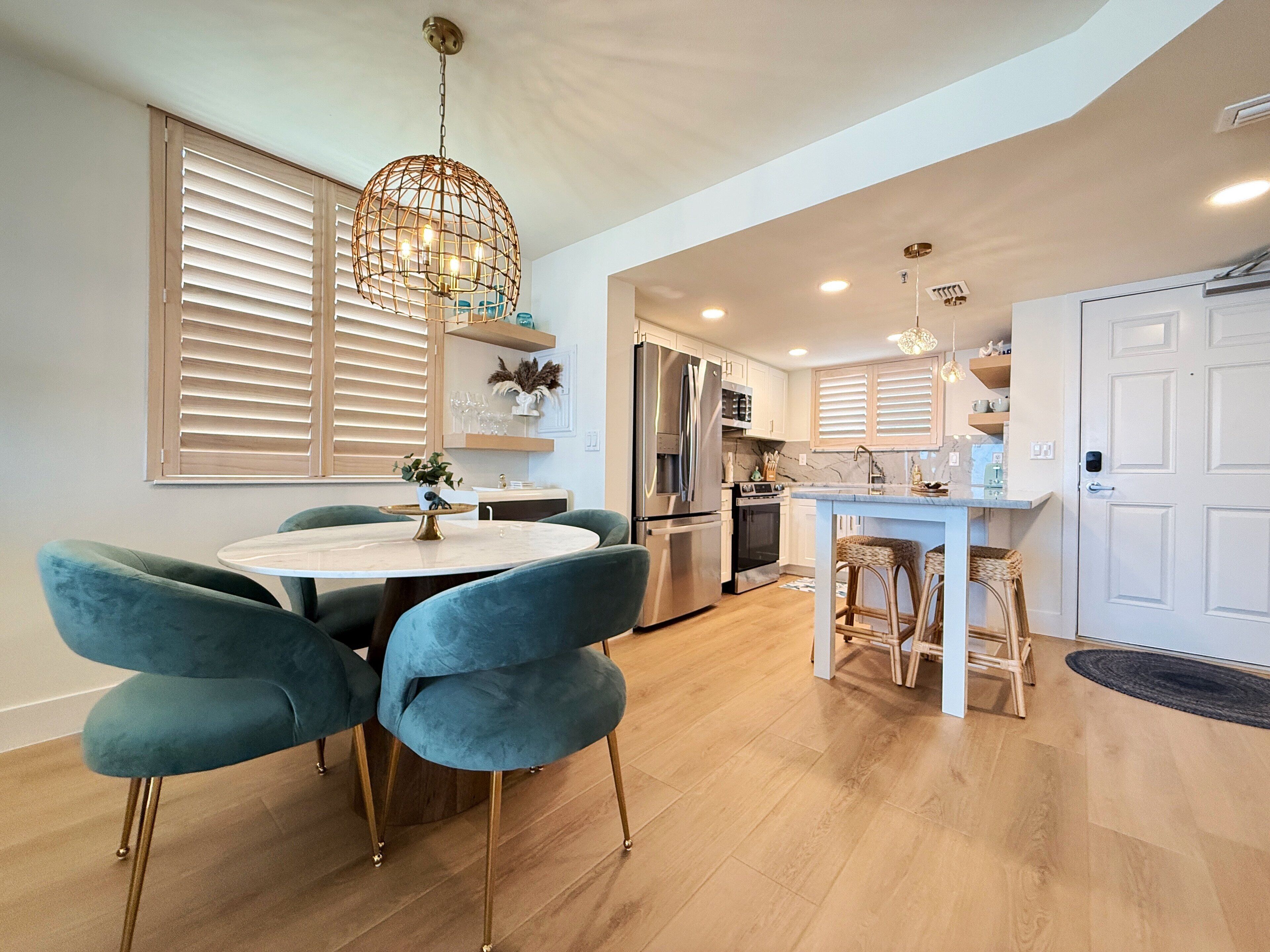 A modern kitchen with a central island, stainless steel appliances, and a dining area with blue chairs.