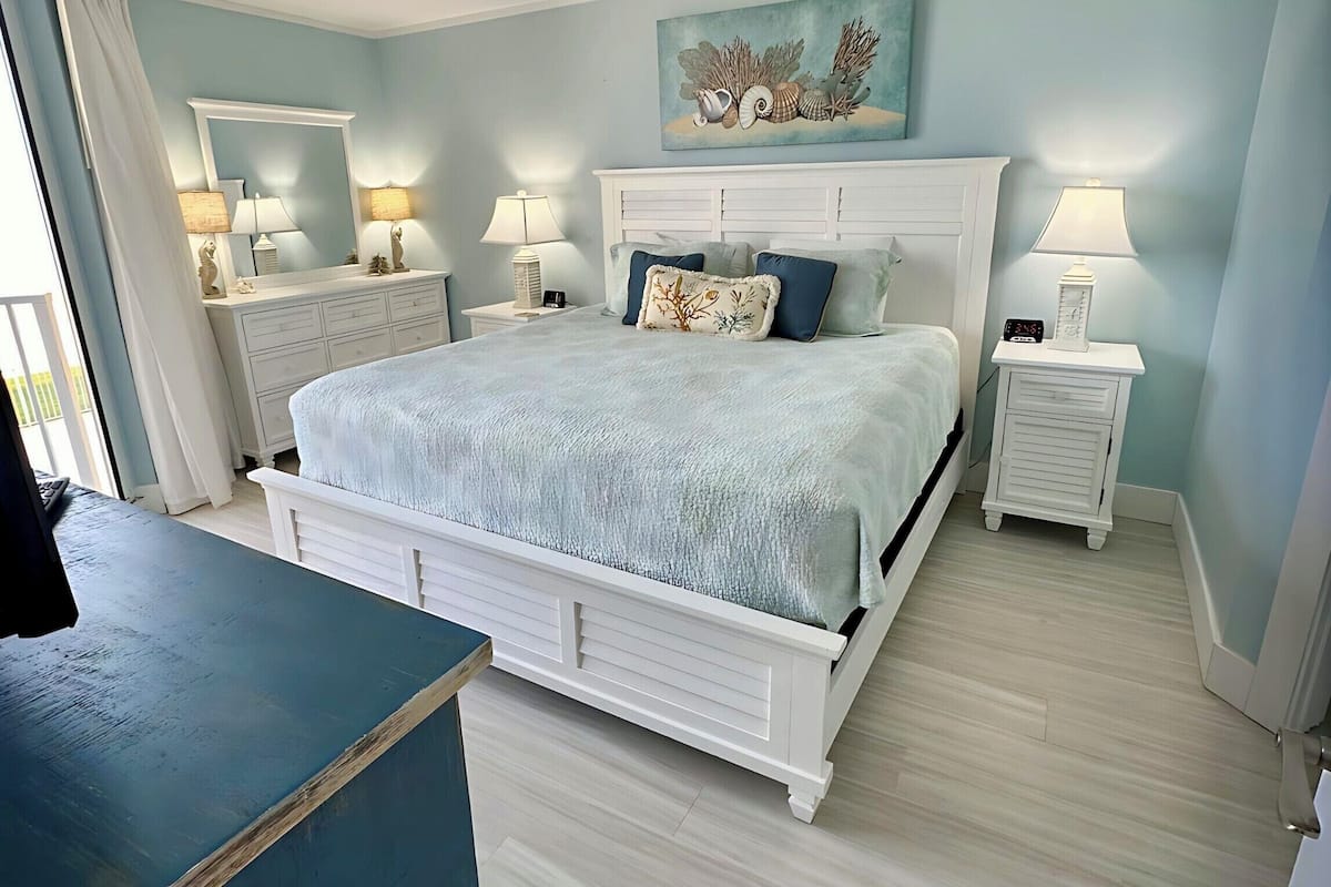 Une chambre à coucher avec un lit, des tables de chevet, une commode et un tableau au mur.