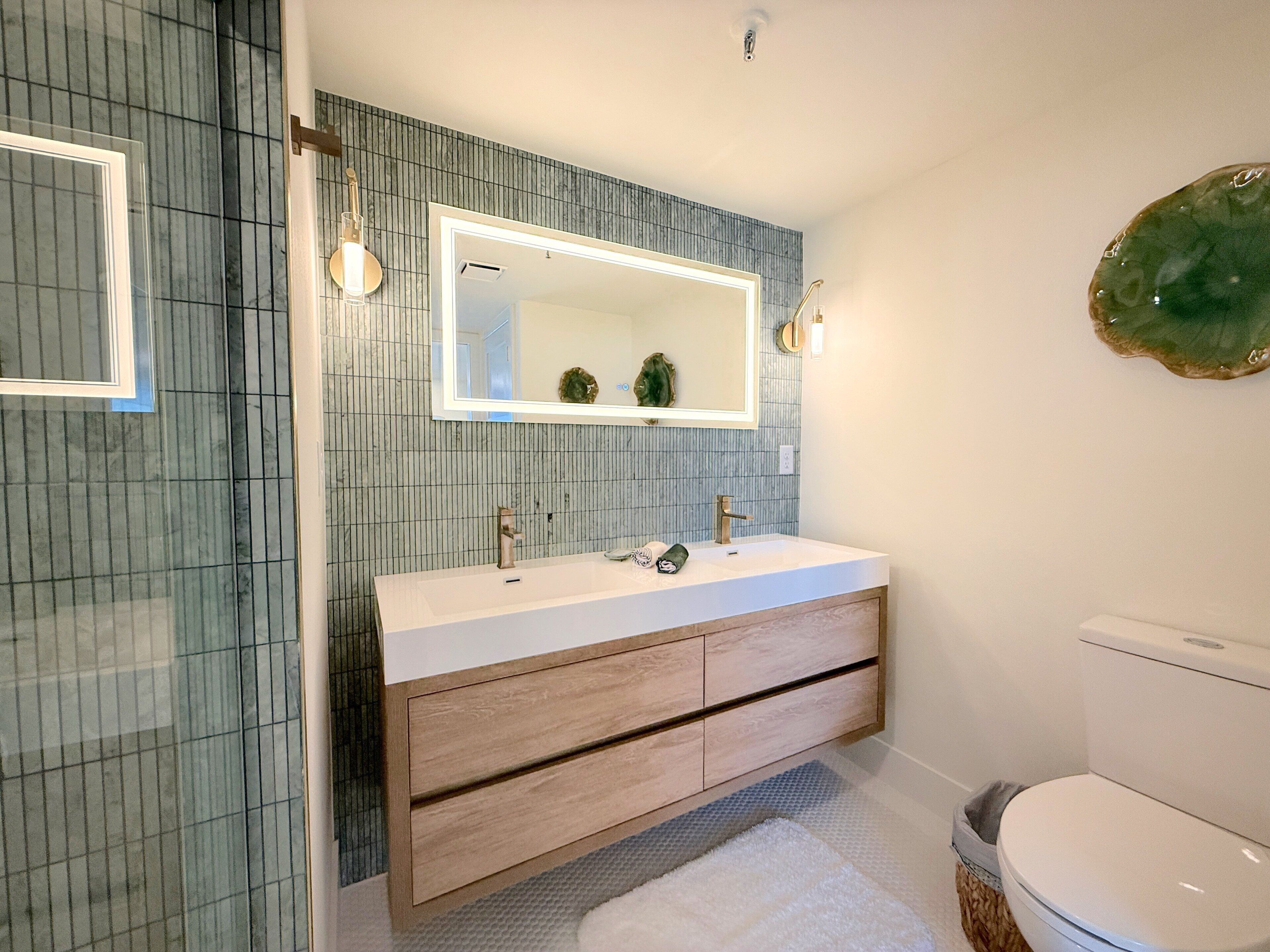 A bathroom with a white sink, wooden vanity, and a large mirror.