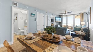 Une cuisine moderne avec une table à manger en bois, un four encastré et une grande fenêtre laissant entrer la lumière naturelle.