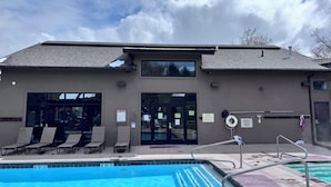 A building with a pool, including a sign for pool rules and a caution sign.
