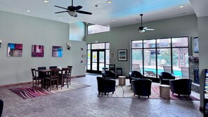 A spacious indoor area with ceiling fans, a pool view, and a dining area with chairs and tables.