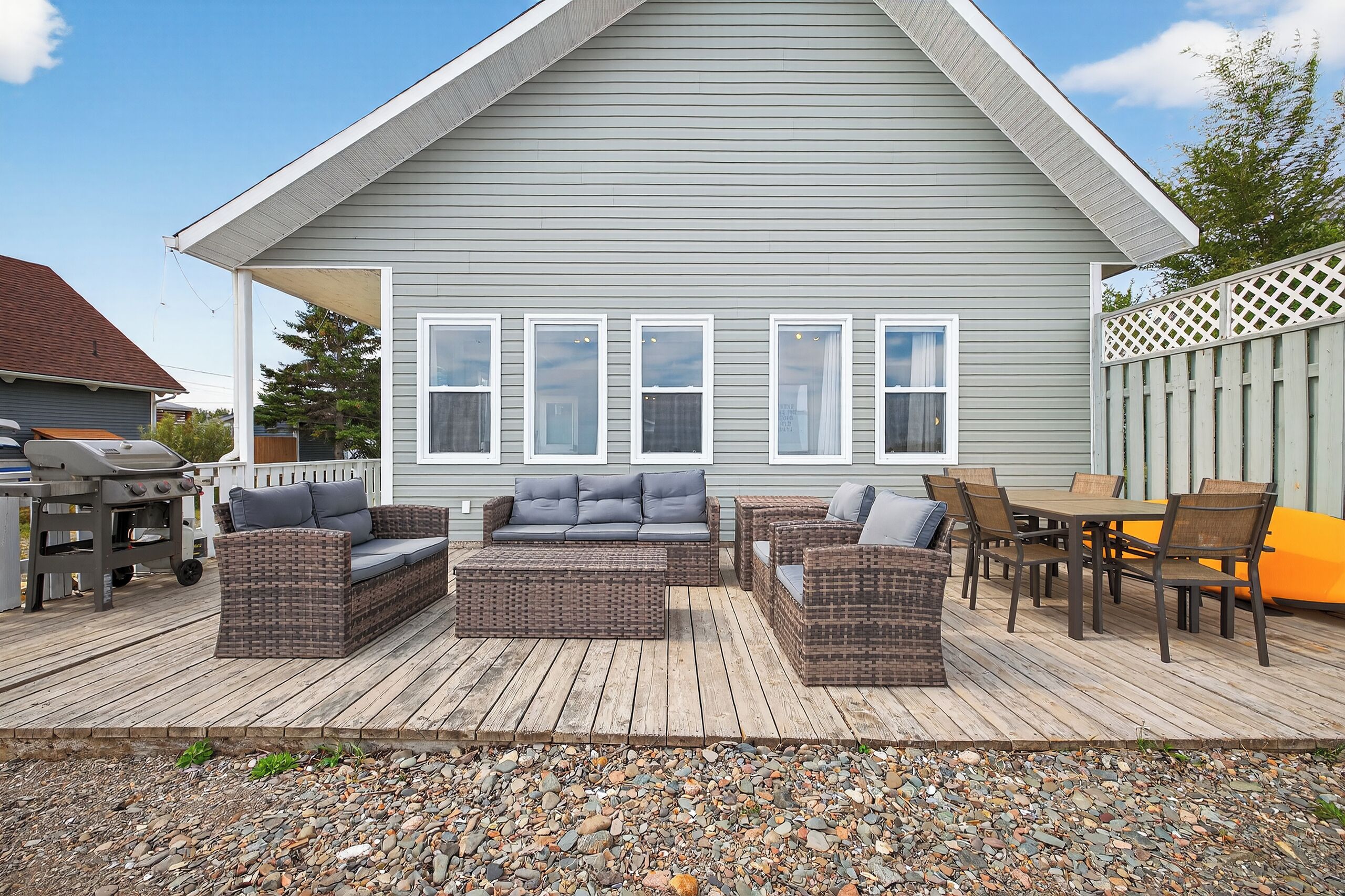 Une terrasse dotée de meubles en osier, d’un barbecue et d’un sol en bois.