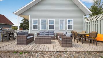 Une terrasse dotée de meubles en osier, d’un barbecue et d’un sol en bois.