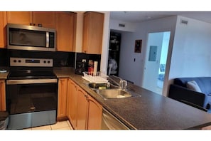 A kitchen with wooden cabinets, a microwave, an oven, and a sink.