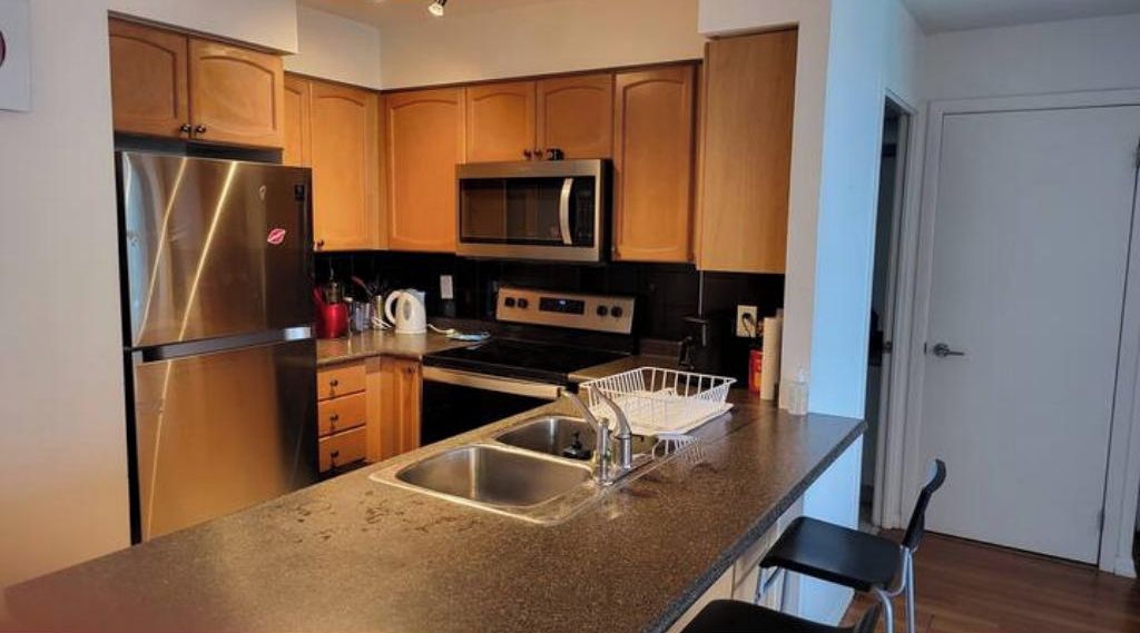 A kitchen with stainless steel appliances, wooden cabinets, and a granite countertop.