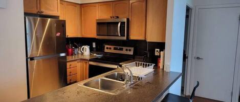 A kitchen with stainless steel appliances, wooden cabinets, and a granite countertop.
