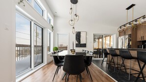 Una cocina moderna con encimera negra, electrodomésticos de acero inoxidable y una lámpara colgante.