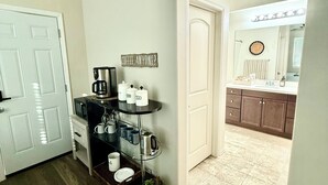 A kitchen with a coffee station, a sink, and cabinets.