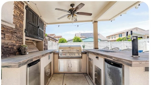 An outdoor kitchen with a built-in grill, dishwasher, and a ceiling fan.