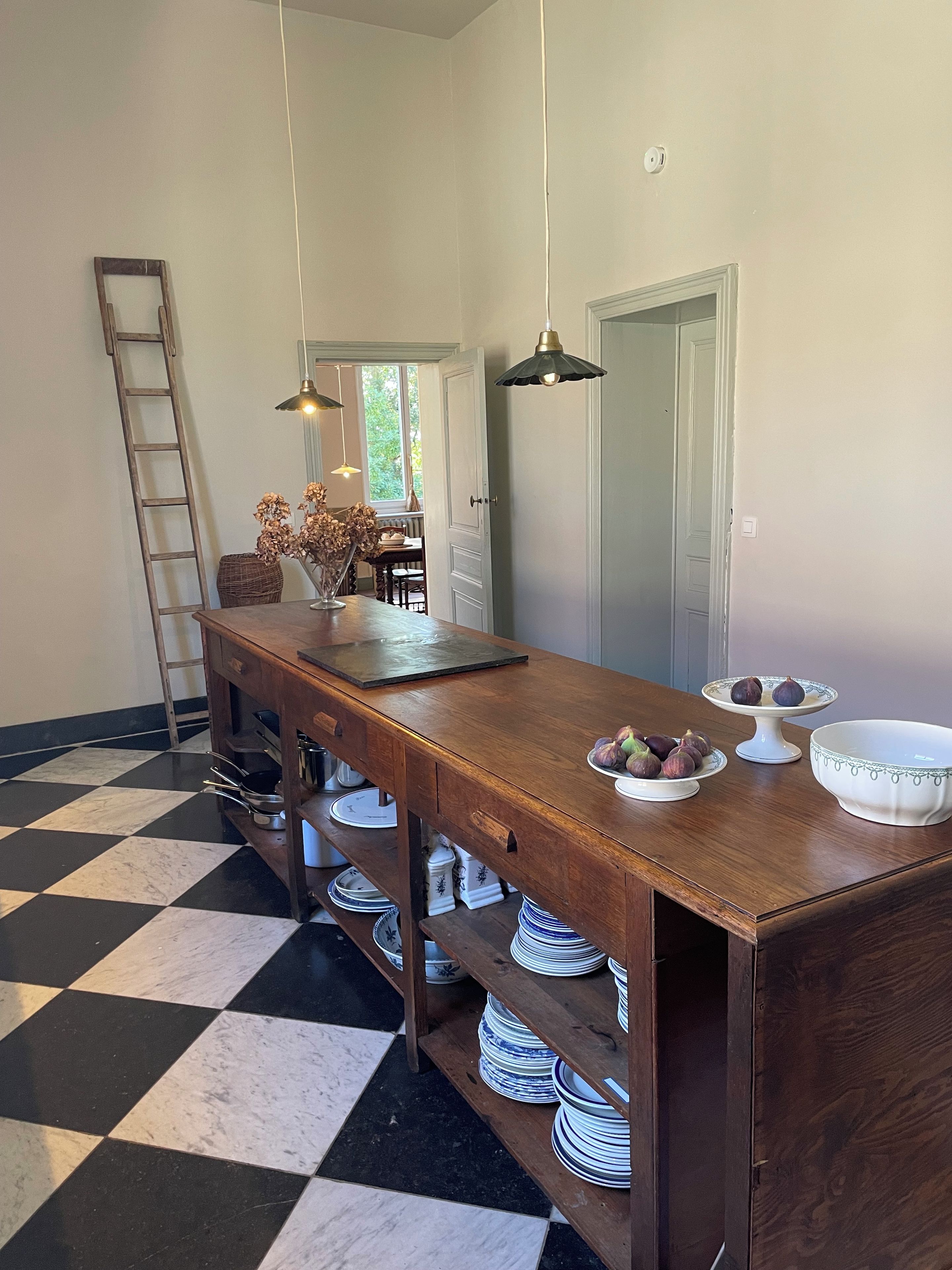 Un espace repas avec une table en bois, des lampes suspendues et un sol à carreaux.