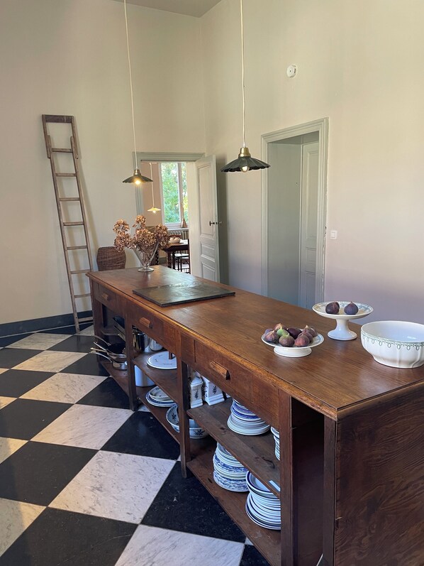 Zona pranzo con tavolo in legno, lampade a sospensione e pavimento a scacchi.