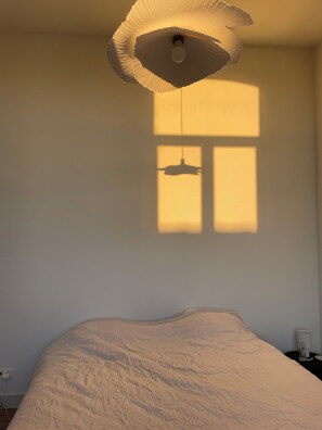 Una stanza con un letto, un lampadario e una finestra che proietta un'ombra.