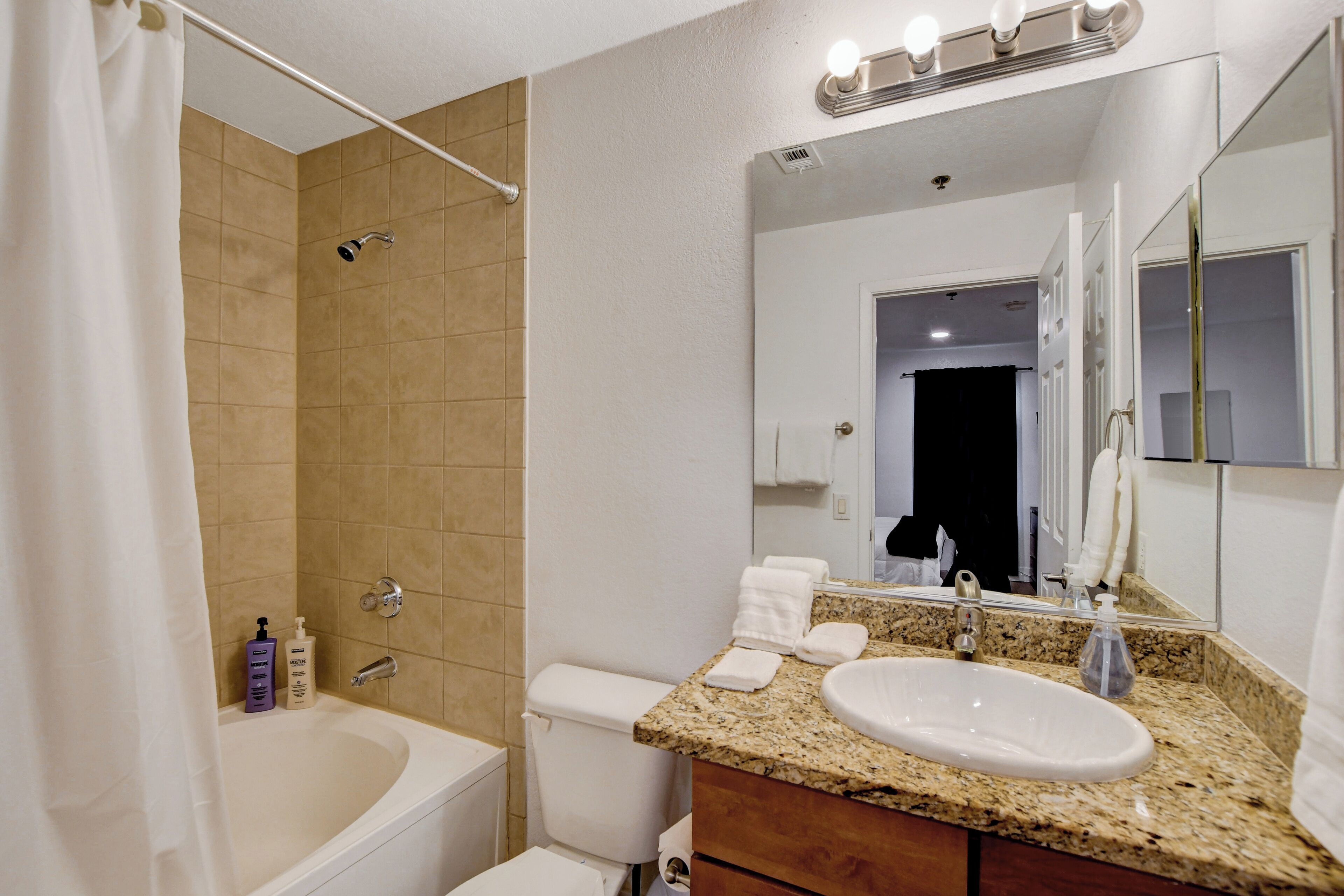 Un baño con bañera, inodoro, lavabo y espejo.