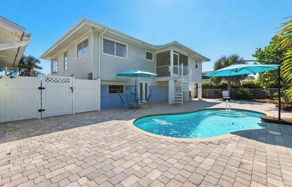 Ein zweistöckiges Haus mit Swimmingpool, überdachter Terrasse und eingezäunter Garten.
