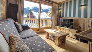 Un salon confortable avec un canapé, une table basse et un téléviseur posé sur un meuble en bois.