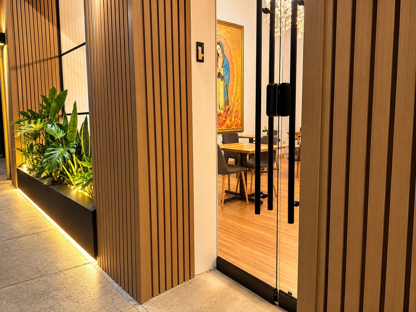 A modern interior with a wooden panel wall, a plant display, and a dining area with chairs and a table.