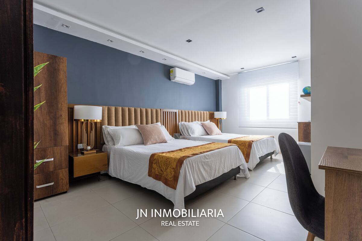 Een moderne hotelkamer met twee bedden, een houten garderobe, een bureau en een stoel.