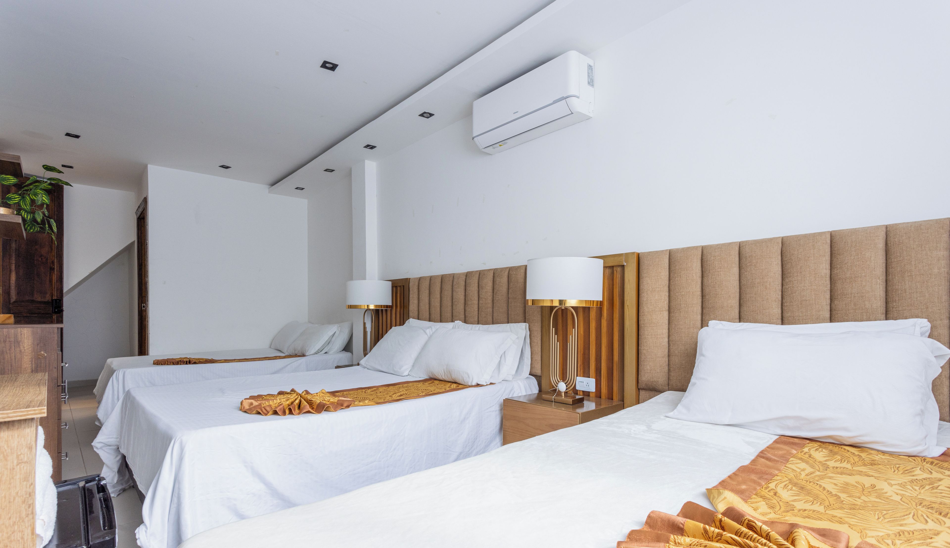 A hotel room with two beds, a wooden headboard, bedside lamps, and a minibar.