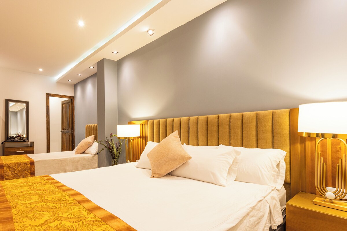 A hotel room with two beds, a large mirror, and a nightstand with a lamp.
