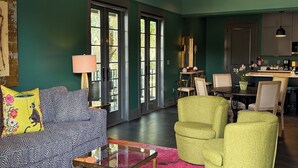 A spacious living room with a green wall, a large window, and a kitchen area.