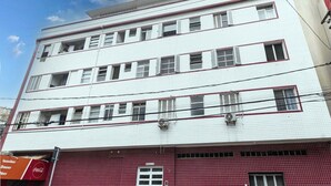 A multi-story building with a white facade and red accents. - Apto Pet-friendly a 400m da Praia do Boqueir o (Praia Grande)